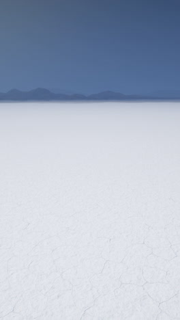 a vast expanse of white salt flats stretches out to the horizon under a clear blue sky.