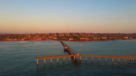 Los-Drones-Orbitan-Alrededor-Del-Muelle-De-Ocean-Beach-En-San-Diego,-California,-Durante-Los-Cálidos-Colores-Del-Atardecer