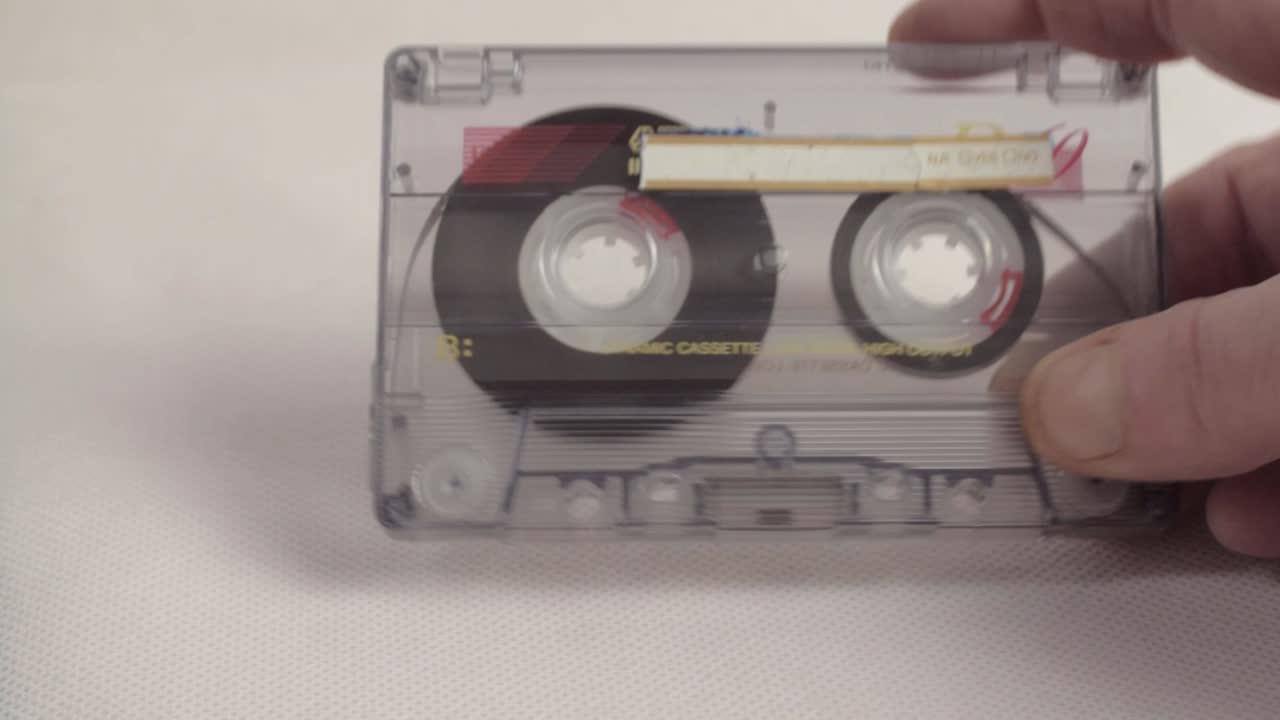 Hand holding retro cassette tapes into radio cassette player close up shot
