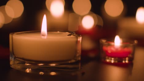 close up of romantic lit red and white candles burning on black background with bokeh lighting 1