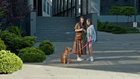 mother and daughter taking pictures of their dog in city park