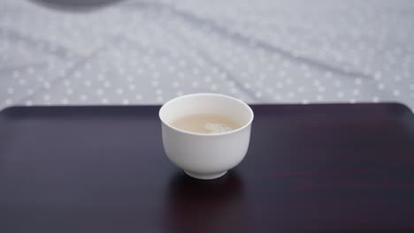 porcelain teapot pouring tea a beautiful white teacup on a wooden tray