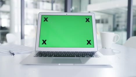 portátil con pantalla verde en la oficina
