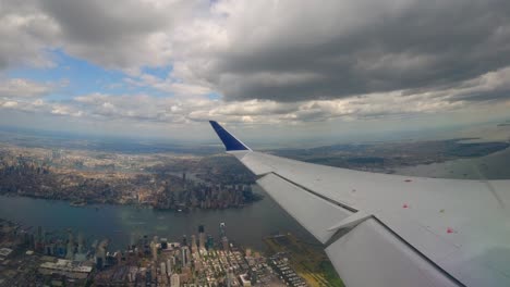 plane window view flying over jersey city with manhattan, brooklyn, and queens in the background in the afternoon