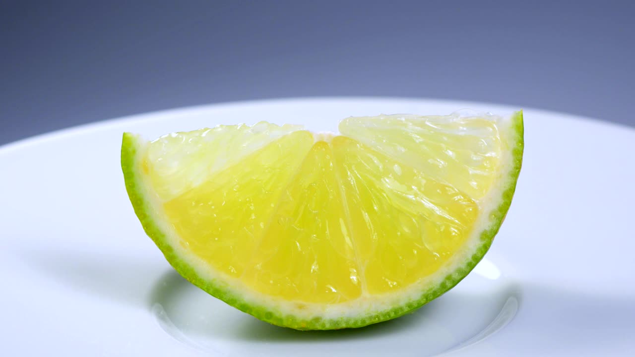 신선한 녹색 레몬 슬라이스는 세부 사항과 함께 스튜디오에서 천천히 회전하고 있습니다.