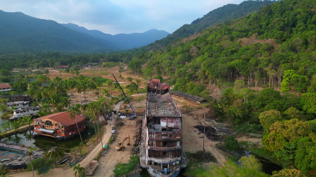 Abandoned resort showing decaying buildings, surrounded by palm trees and a lake, in Koh Chang, Thailand. Wonderful aerial view flight fly reverse drone