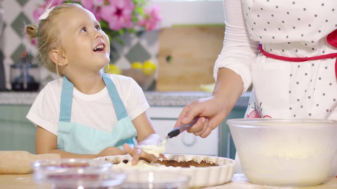 sonriendo, una niña feliz horneando con su madre.