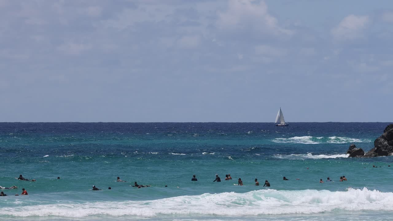서퍼 들, 수영자 들, 항해 보트 들 이 있는 해변 장면