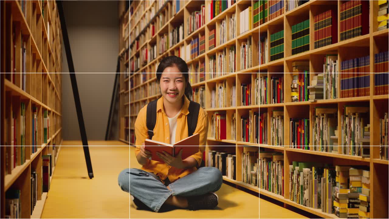 pantalla tomó la foto de una estudiante asiática con una mochila leyendo un libro y luego sonriendo a la cámara mientras estaba de pie en la biblioteca