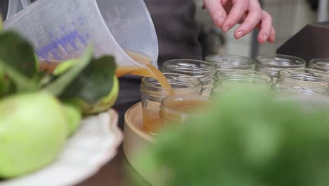 Cook-Pouring-Freshly-Cooked-Apple-Jam-Into-Jars-In-The-Kitchen---Close-Up-Shot