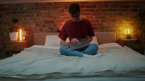 hombre trabajando en la computadora portátil en el dormitorio por la noche