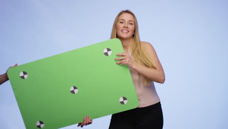 hands are giving an oversized blank card to a stunning smiling young lady