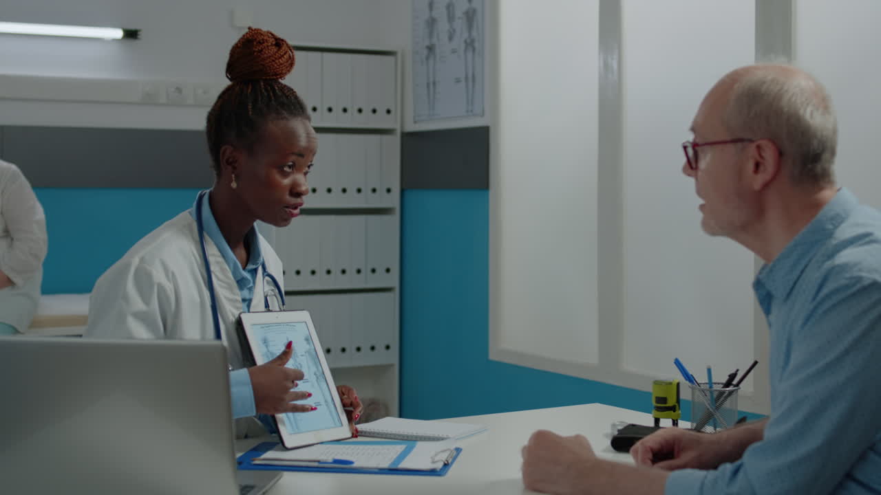 Senior patient looking at illustration of skeleton on tablet