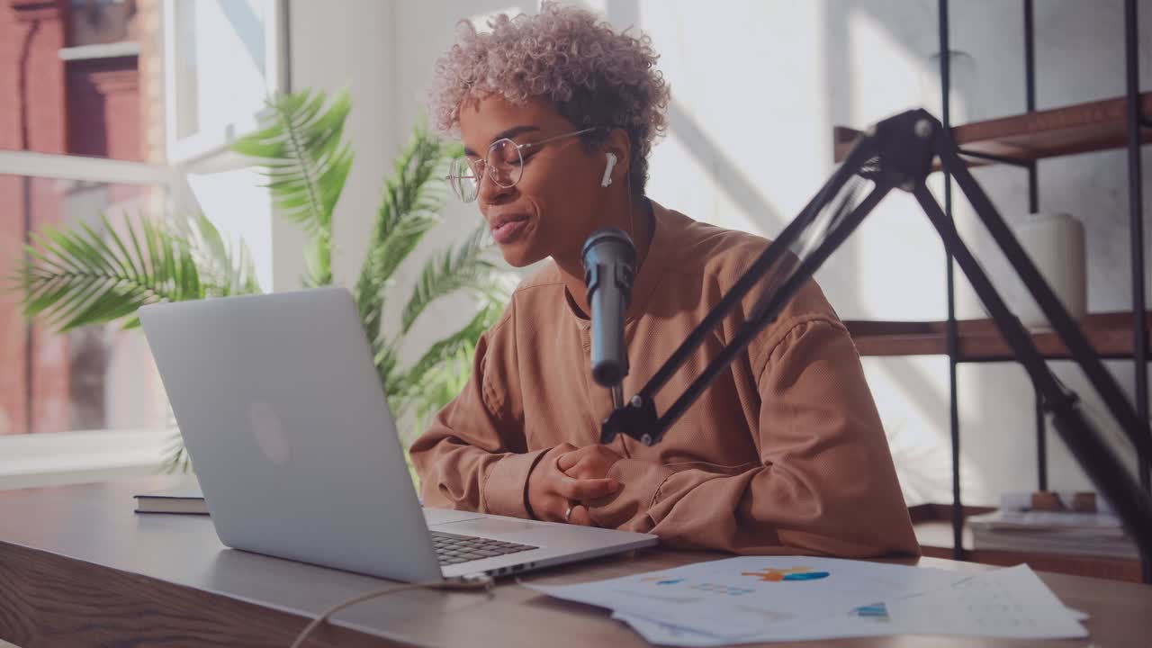 Woman blogger streams online using laptop studio microphone and earphones