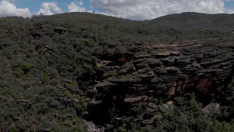 pan giratorio aéreo alrededor de la piedra de cocodrilo que sobresale de la enorme meseta hecha de escamas de formaciones rocosas contra un cielo azul con nubes en el parque andorinhas [golondrinas] en ouro preto