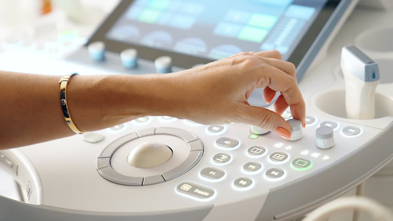 Hand of female doctor work at ultrasound machine. Medic performs sonography examination of a patient. Close up.