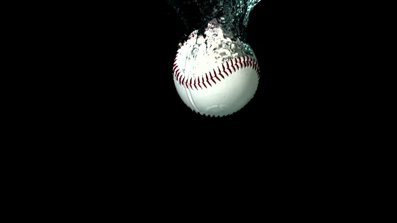Palla da baseball che cade nell'acqua su sfondo nero