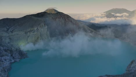 the smoke of sulfur mining mountain volcano crater with acidic of kawah ijen lake in east java indonesia.