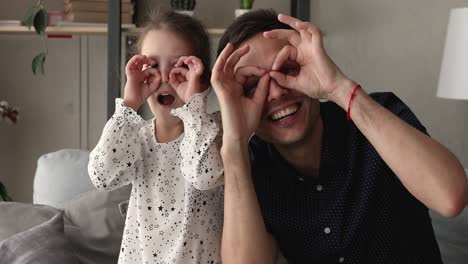 father daughter look at camera showing eyewear shape with fingers