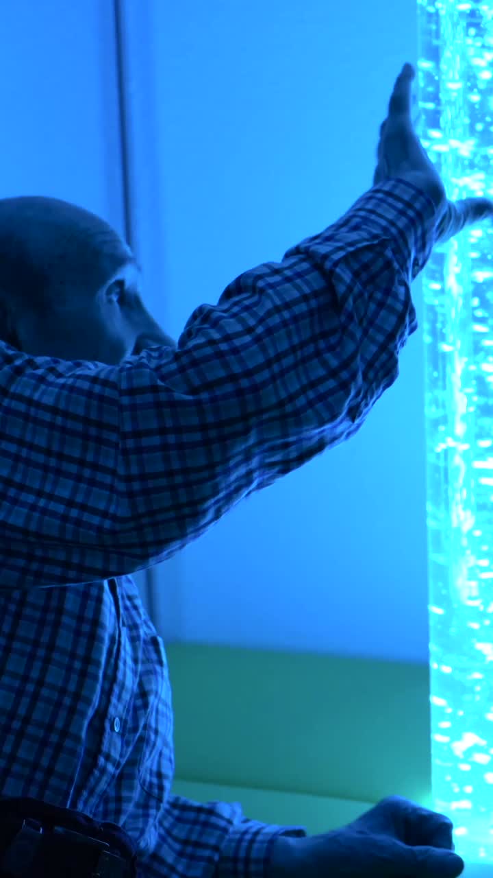 Elderly man enjoying a sensory room with bubble wall