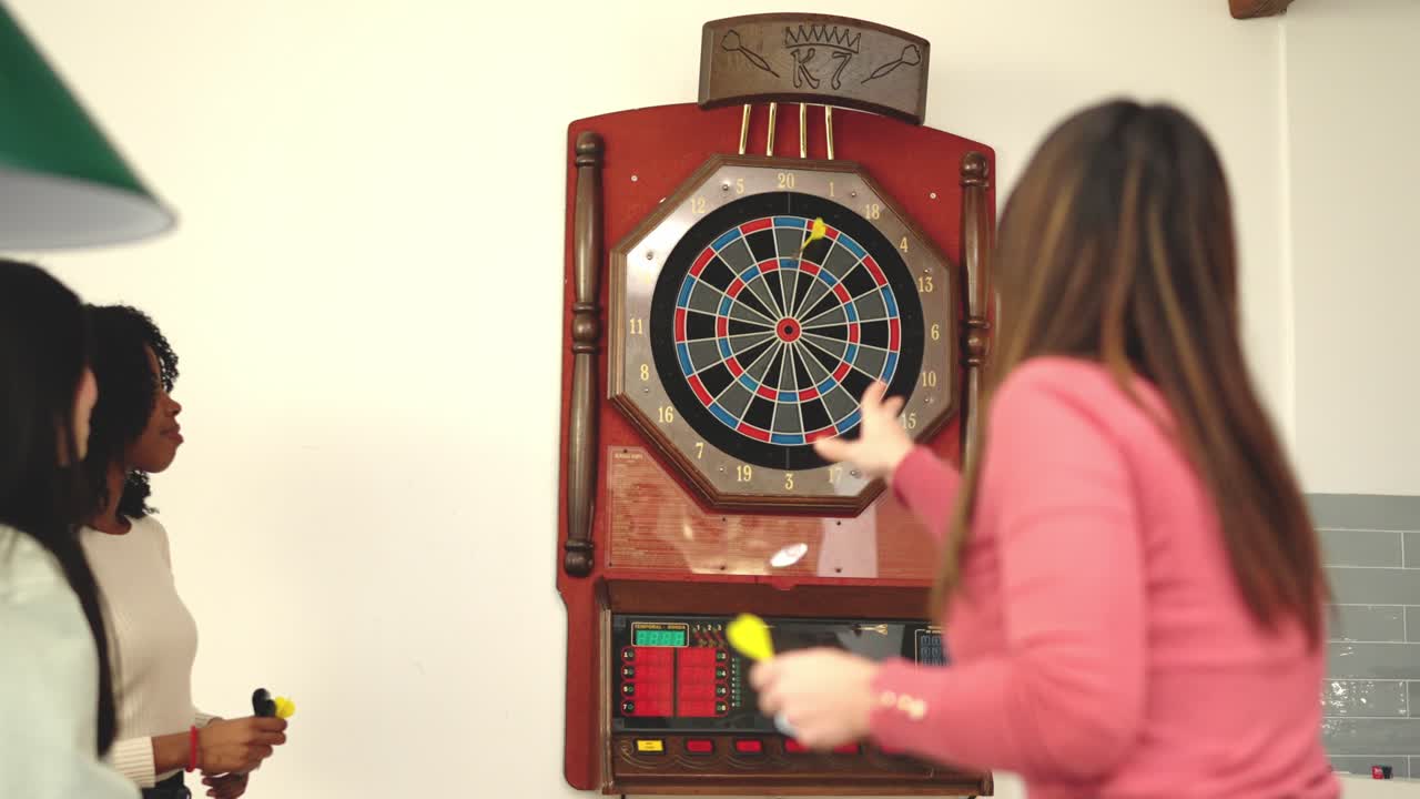 Group of multi-ethnic friends playing darts at home