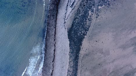 AERIAL---Top-down-view-of-coastline-of-Island-Davaar,-Kintyre,-Scotland,-rising