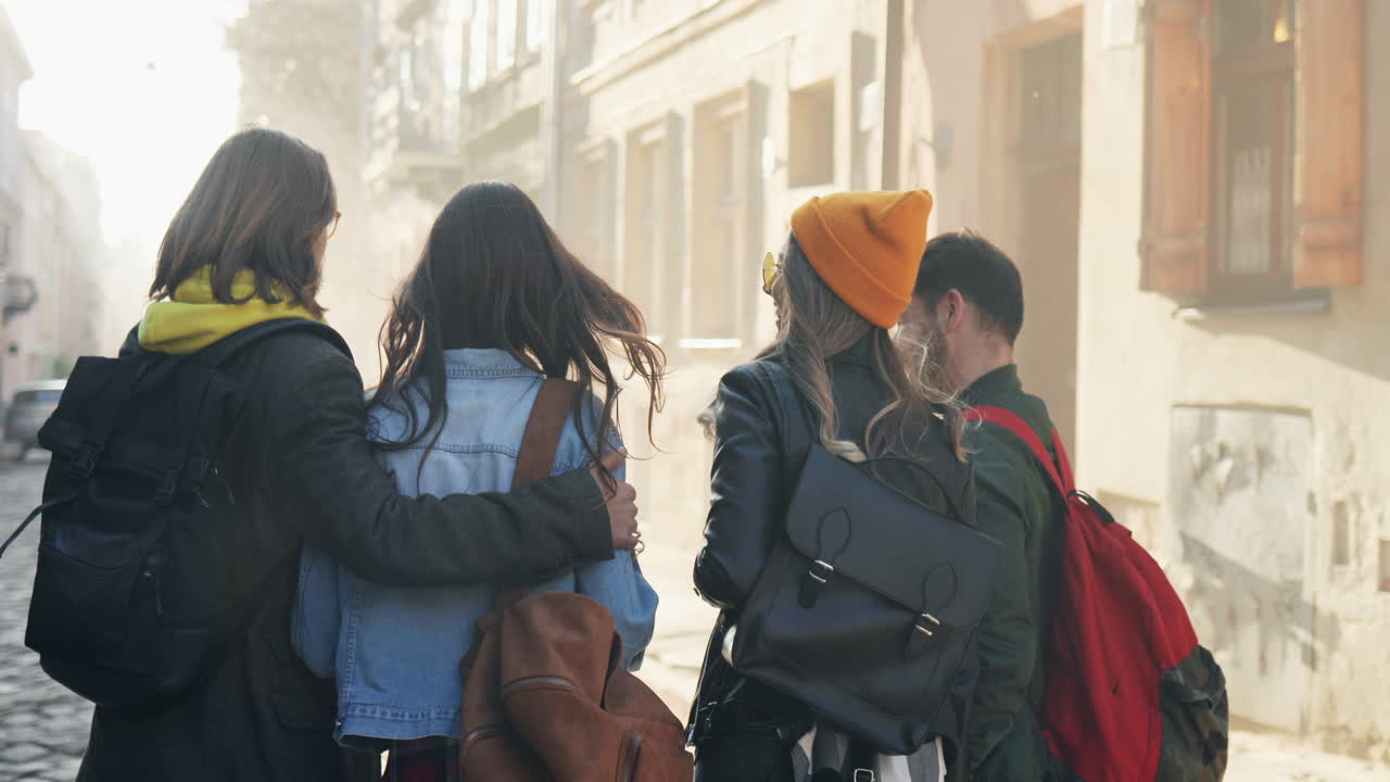 vista trasera de un grupo caucásico de amigos caminando por la calle y hablando en un agradable día soleado en la ciudad