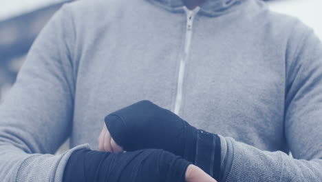 close-up view of sportsman wrapping his hands with black cloth on a cloudy morning