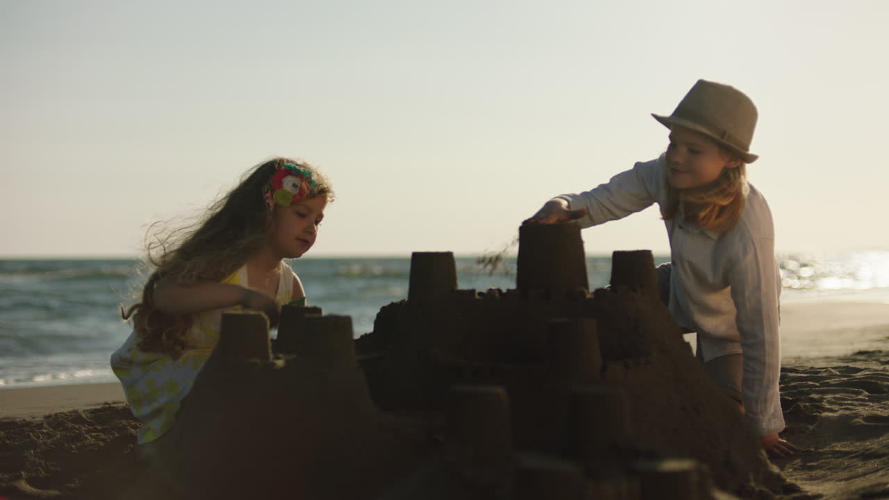 해가 지면 해변에 모래 성을 짓는 아이들