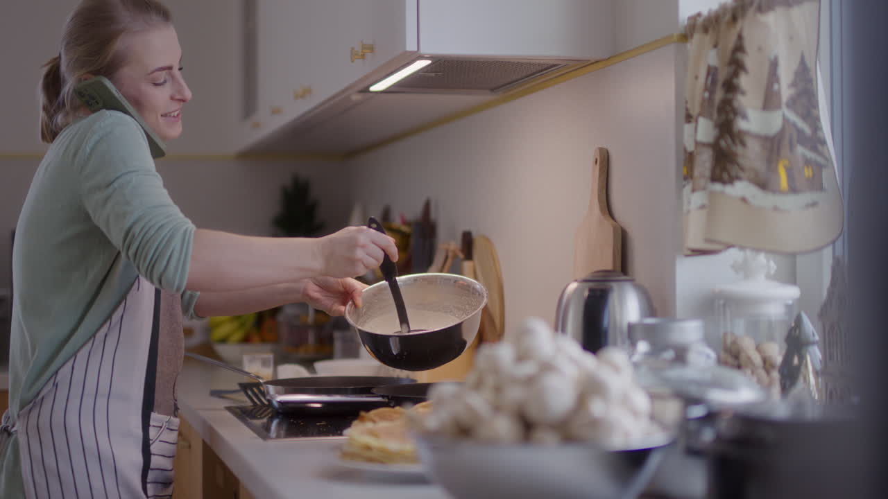 mujer preparando la cena en la cocina y hablando por teléfono