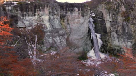 las cascadas caen por un acantilado rocoso rodeado de follaje de otoño en la patagonia, argentina.