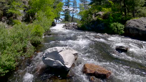 fast rushing water flows around a white granite boulder in river rapids in slow motion, fixed wide in 4k