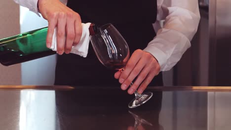 bar tender pouring red wine in glass