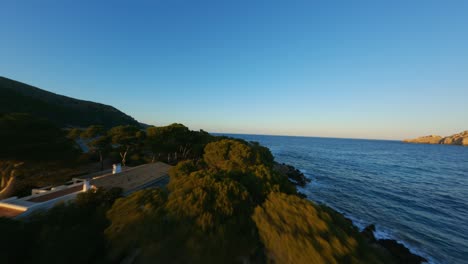 drone de carreras de fpv volando sobre la línea costera de la playa hacia el océano en la hora dorada del atardecer