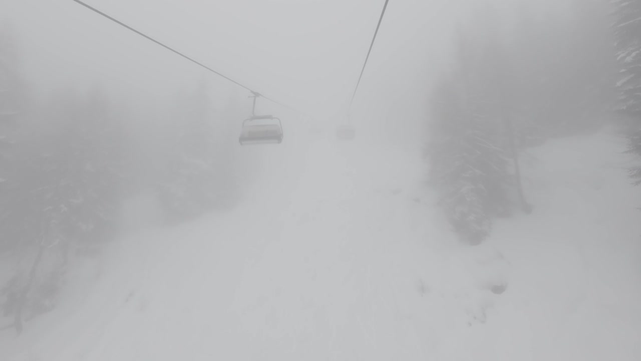 유럽 알프스 산맥의 눈 인 숲에서 두꺼운 안개 속에서 의자 엘리베이터를 타고