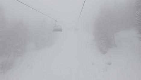 montando en un teleférico en una fuerte niebla en un bosque nevado en los alpes, europa