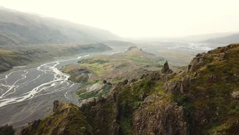 stunning aerial view of the þórsmörk valley in iceland, showcasing a winding river flowing through rugged mountains, creating a dramatic and awe-inspiring landscape, drone pulling out shot