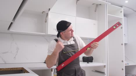 funny and fun kitchen furniture assembler simulates playing the guitar with a construction level funny and fun kitchen furniture assembler simulates playing the guitar with a construction level happy young worker of european appearance at work