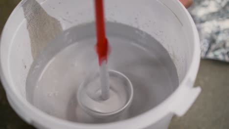 drill paddle mixer on a bucket with white paint, diy tools and accessory, banner. the white paint is mixed in a bucket with a drill