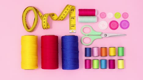 sewing materials and items appear on pastel pink background. stop motion flat lay