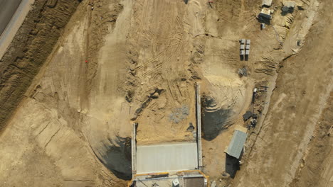 aerial top-down view of bridge under construction with deep excavation