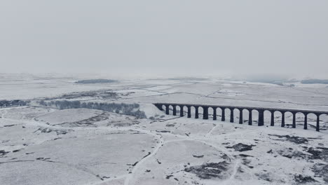 の日の雪のリブルヘッド・バイアダクトの空中ドローンショットを確立するワイド・アングル ヨークシャー・デールズ イギリス