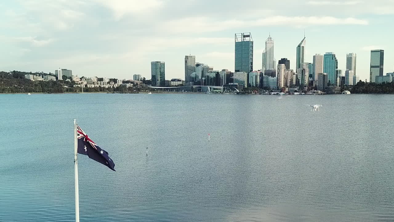Aerial, drone in shot flying close to Australian Flag, river and city skyline in background