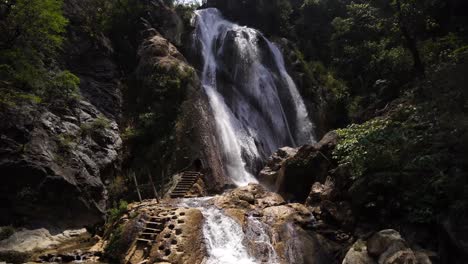cascada alta con escalera y escaleras para subir para ir detrás de las cataratas