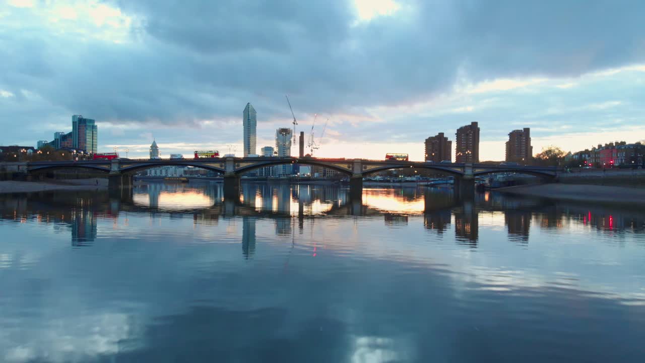 해질녘 배터시 다리와 첼시 항구에서 템스 강 교통 런던 버스의 낮은 드론 샷