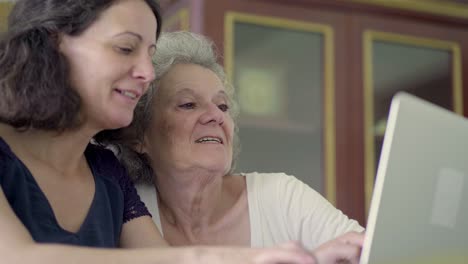 Cheerful-middle-aged-woman-with-her-mother-using-laptop.