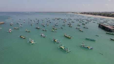 aerial view of indonesian traditional juking boats bobing near the pier on turquoise transparent waves near a tropical island of bali