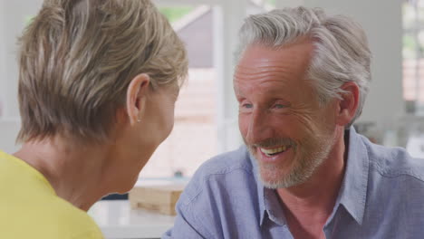 Close-Up-Of-Retired-Couple-Sitting-Around-Table-At-Home-Talking-Together