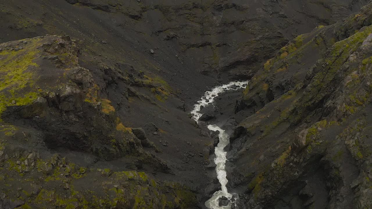 Reveal drone shot of falling river from glacier in the mountains, Vatnajokull, Iceland