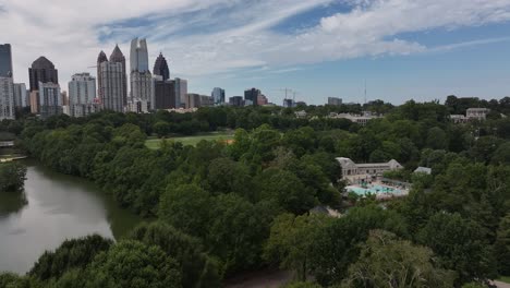 Aerial-panoramic-shot-of-Atlanta-City-with-skyline-and-scenic-river-between-green-trees-in-park,-Georgia,-America---circling-establishing-drone-shot